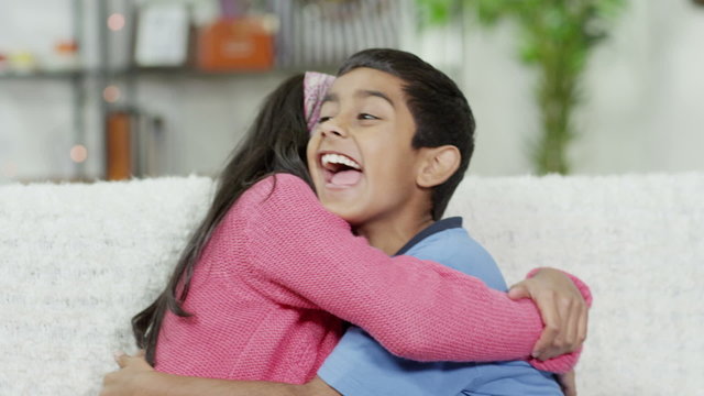 Brother and sister hugging each other and laughing