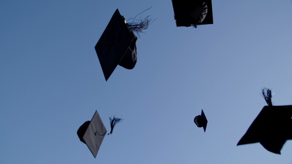 Graduation caps are tossed into the air on a bright sunny day