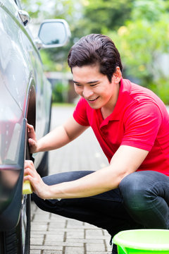 Asian Man Cleaning Car Rims With Sponge