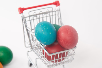 Easter colorful painted eggs in the shopping cart and near the t