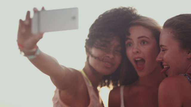 Multi ethnic group pulling faces for selfie at beach