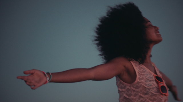Teenage afro girl enjoying sunset at beach