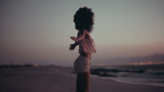 Teenage afro girl enjoying sunset at beach