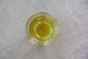 Glass With Olive Oil Standing On A Canvas And Photographed From