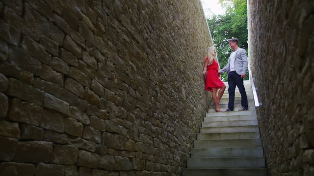 Attractive young couple walking down a set of stone stairs pause to share a kiss