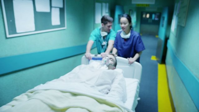 Hospital emergency team rush a patient on a gurney to the operating theatre.