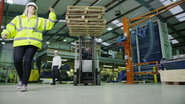 Team of busy warehouse workers lifting and moving empty wooden pallets