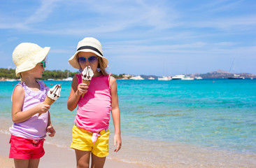 Little happy girls eating ice cream on tropical beach