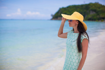 Fototapeta na wymiar Young fashion woman in hat and dress on the beach
