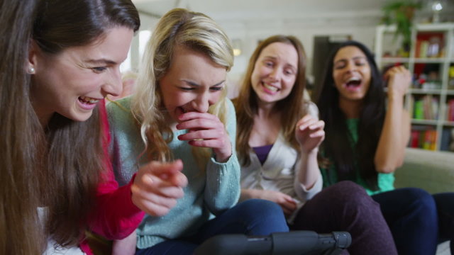 Happy casual young female friends laughing at what they see on a computer tablet