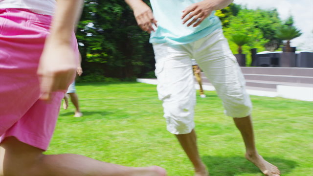 Athletic group of male friends play football in the garden of contemporary home
