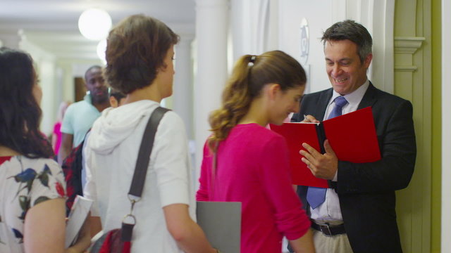 Teacher checking the register as his students enter the classroom