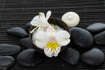 Fototapeta na wymiar White orchid with salt in bowl and black stones on mat