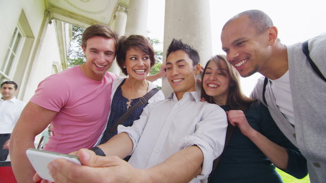 Happy group of student friends pose to take their picture with a smartphone