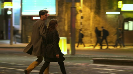 Attractive couple in casual dress crossing the road in London at night - Powered by Adobe
