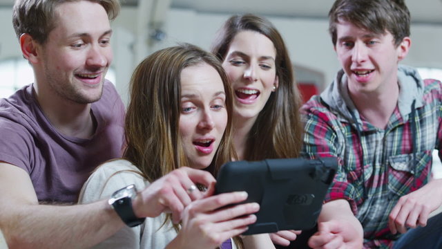 Happy casual group of young friends relaxing with a tablet computer