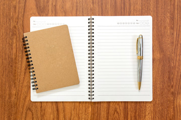 Blank notebook with a pen on wood background