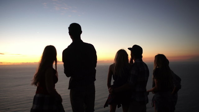 Teens looking at the ocean after sunset on a mountain