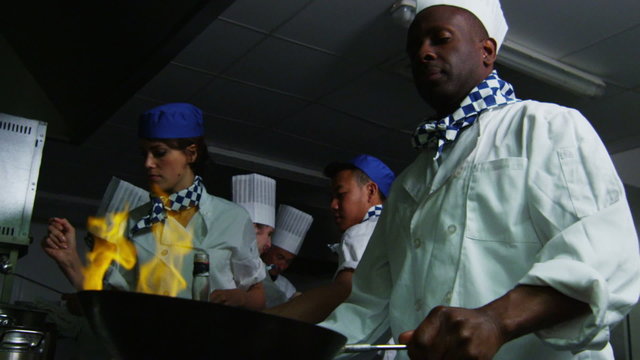 Professional chef in a restaurant kitchen cooking flambe style