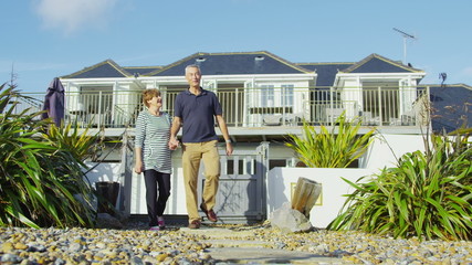 Happy attractive mature couple on vacation take a walk along the beach - Powered by Adobe