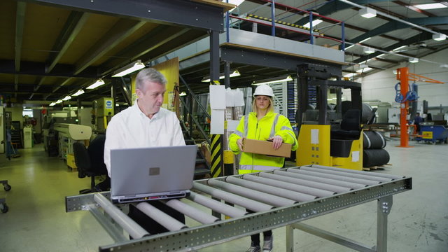 Workers in a warehouse with a laptop computer are preparing goods for delivery