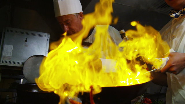 Professional chef in a restaurant kitchen cooking flambe style