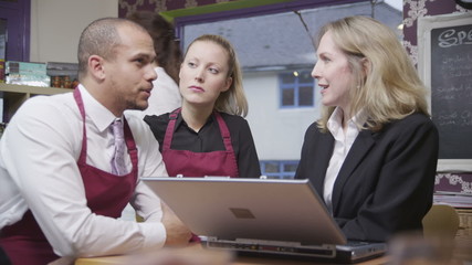 Attractive male and female coffee shop workers discuss work with their manager