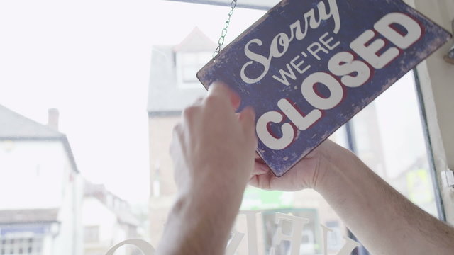 'Open' sign is turned to 'Closed' in a storefront window