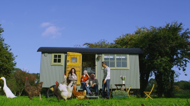 Extended family group outside quaint caravan with chickens and ducks