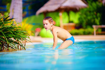 cute wet kid, boy enjoying vacation in tropical pool