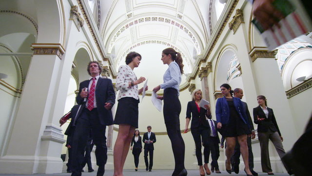 Young female business delegates stand and chat in busy conference building