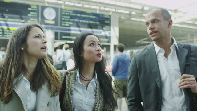 Young professionals looking at the departure boards at a busy railway station