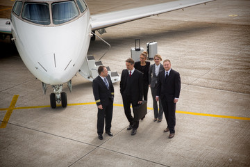 executive business team in front of corporate jet talking to pil