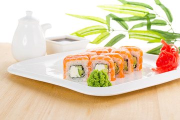 Sushi set on white plate over wooden background