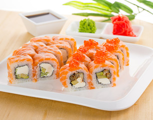 Sushi set on white plate over wooden background