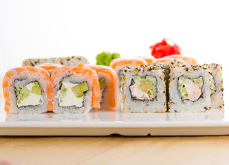 Sushi set on white plate over wooden background