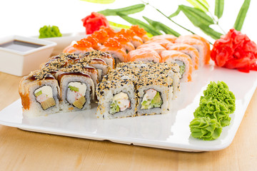 Sushi set on white plate over wooden background