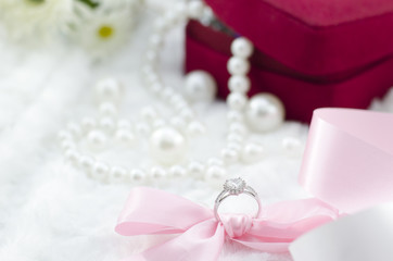Fototapeta na wymiar Diamond ring with pink ribbon and pearl necklace