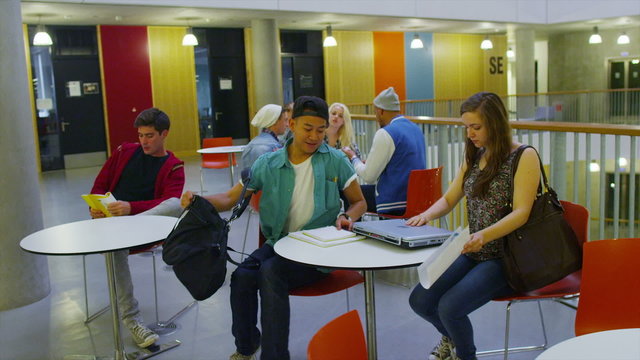 Cheerful diverse student group in large modern university building.