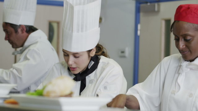 Happy Team Of Chefs In A Commercial Kitchen, Working And Chatting Together