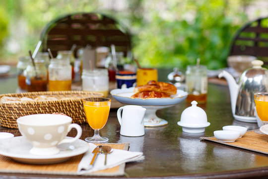 Table laid for breakfast outside with various jams coffee, crois