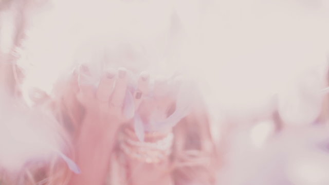 Boho girl blowing brightly coloured pink feathers