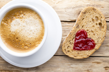Fresh coffee. Grain slice of bread with jam heart shape.