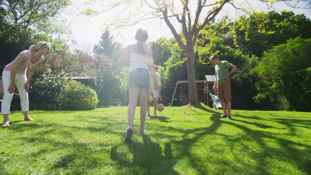 Young girl playing soccer with her family outdoors on a sunny day