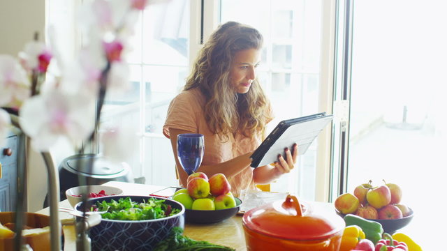 Young woman relaxing at home with computer tablet and a glass of wine
