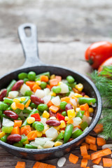 Mixed vegetable meal in old black frying pan closeup and ingredi