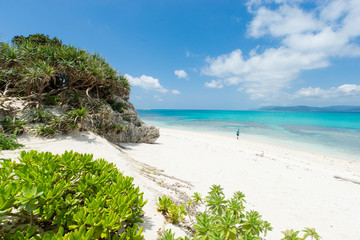 Man overlooking view of tropical white sand beach paradise lagoon full of healthy coral reef in Okinawa