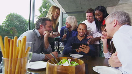Cheerful diverse adult group gather round to look at screen of a computer tablet - Powered by Adobe