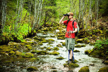 Hiker looking through binoculars in forest