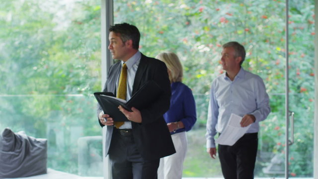 Mature Couple Being Shown Round A Luxury Modern Home By The Estate Agent